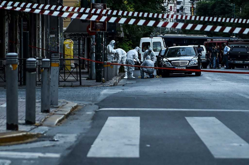 Polisi ahli forensik mencari barang bukti di sekitar mobil yang ditumpangi mantan PM Yunani Lucas Papademos, di Athena, Kamis (25/5/2017) waktu setempat.