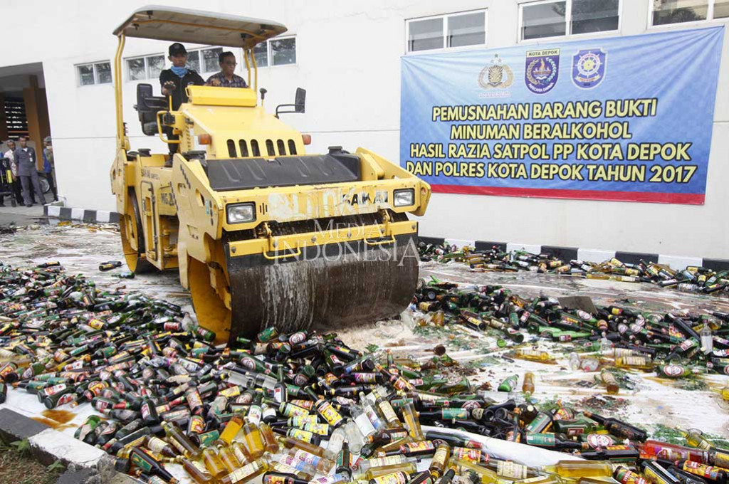 Petugas dibantu alat berat memusnahkan minuman beralkohol di halaman Balai Kota Depok, Jabar. MI/Bary Fathahilah