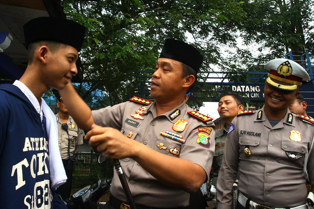Kapolres Metropolitan Tangerang Kota Kombes Pol Harry Kurniawan (tengah) memberikan hadiah peci kepada seorang pelajar yang kedapatan mengendarai motor tidak membawa SIM saat razia Ramadania di Cikokol, Tangerang, Banten.