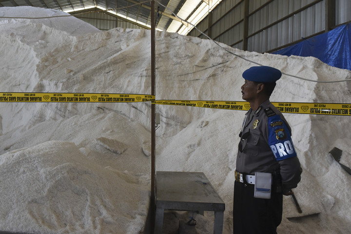 Petugas berjaga di depan garam milik PT Garam (persero) yang disegel di dalam gudang.