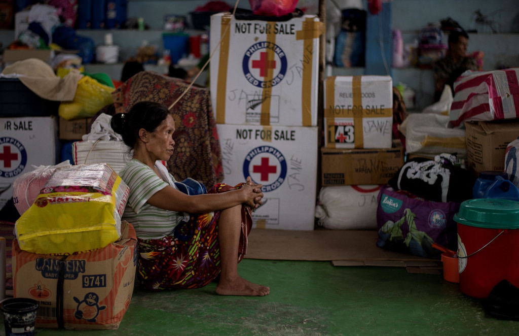 Seorang wanita terpekur di gedung olahraga yang dijadikan tempat penampungan pengungsi. Puluhan warga sipil tewas dalam kontak senjata antara militer dengan milisi.