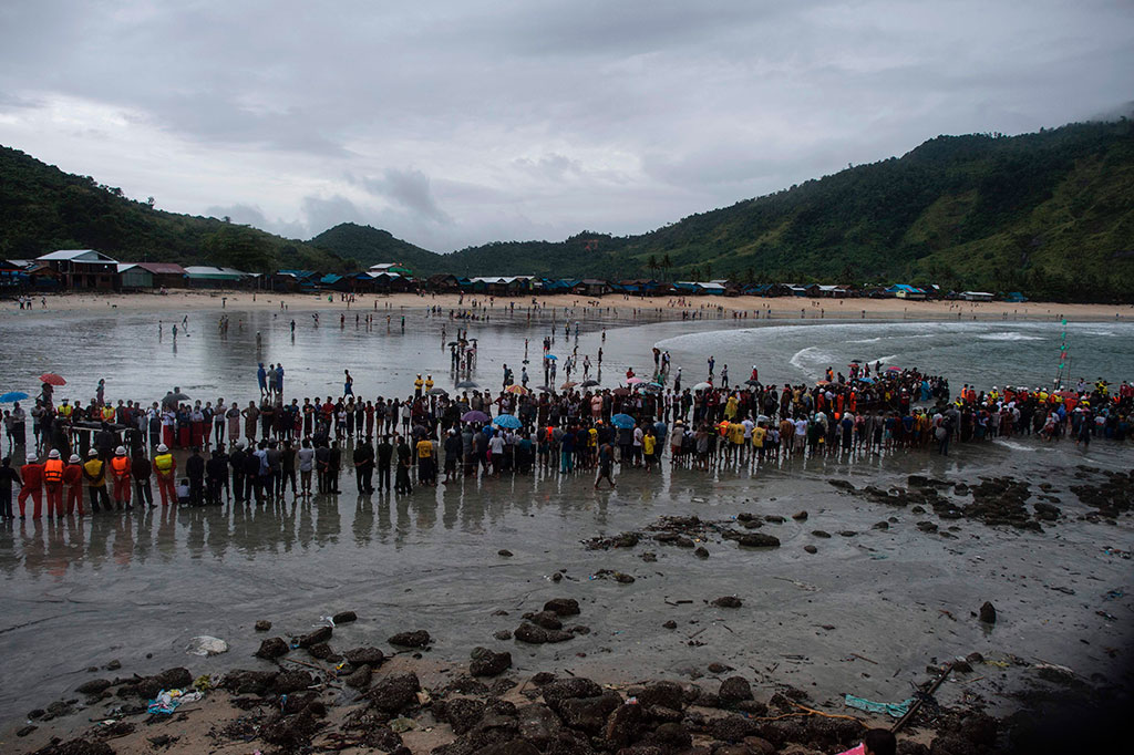 Ratusan orang menunggu anggota militer Myanmar mengevakuasi jenazah korban jatuhnya pesawat, di sebuah pantai di Desa Sanhlan, Lang Lone, Myanmar, Kamis (8/6/2017).