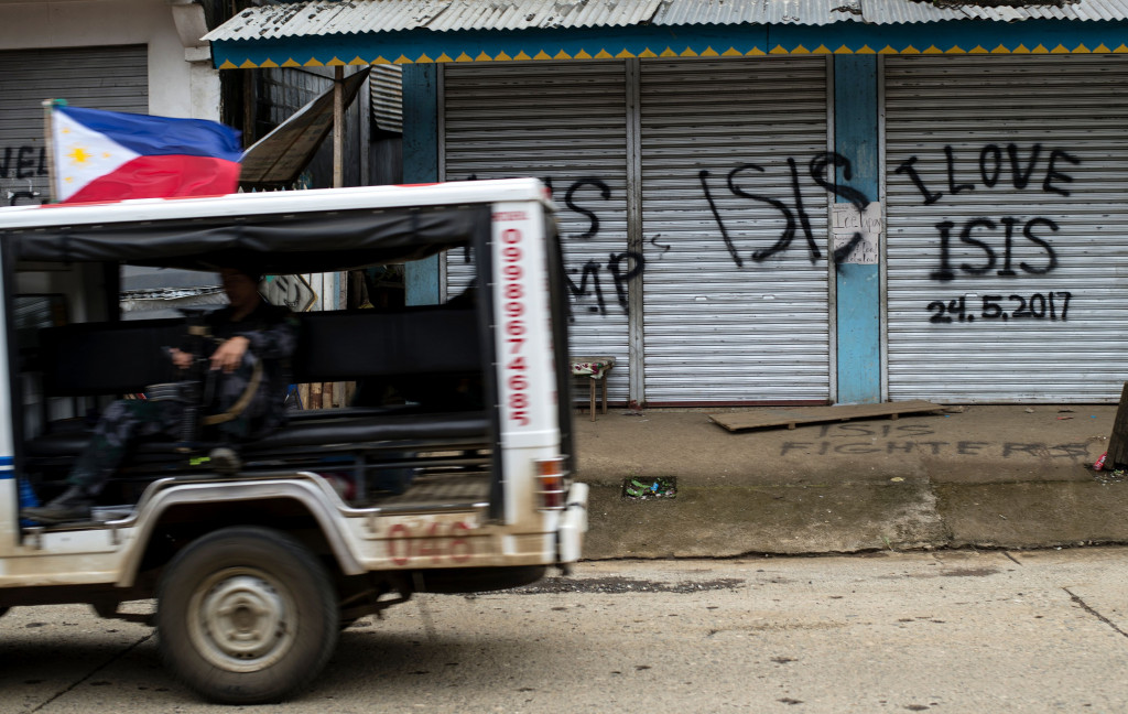 Patroli militer Filipina melintas di depan toko yang pintunya bertuliskan simpati kepada ISIS. 