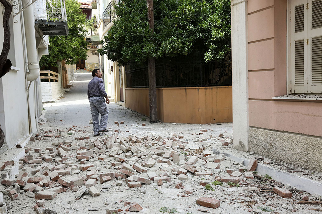 Seorang pria melihat kerusakan beberapa rumah akibat guncangan gempa di Lesbos.