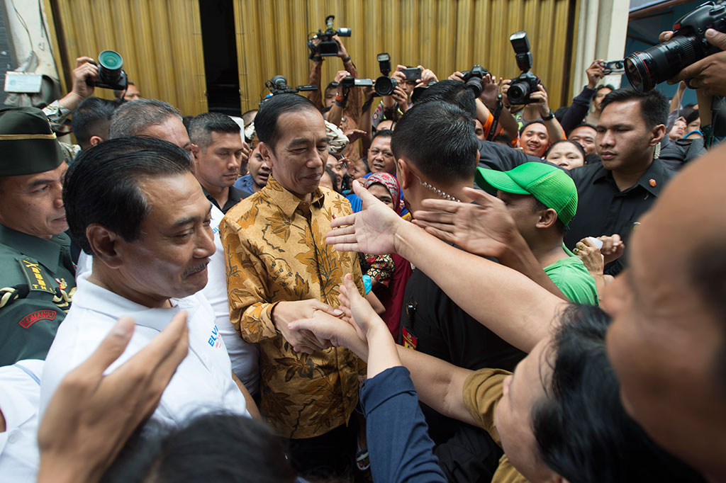 Presiden Jokowi menyalami warga yang mengantre pembagian sembako.