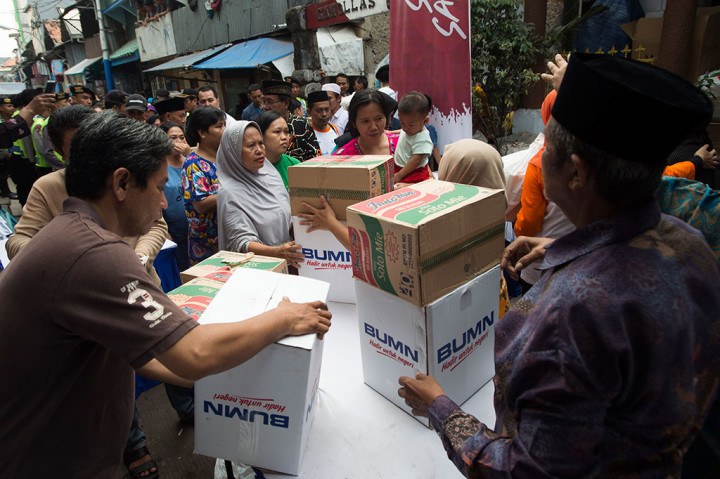 Petugas membagikan sembako kepada warga yang memegang kupon penukaran.