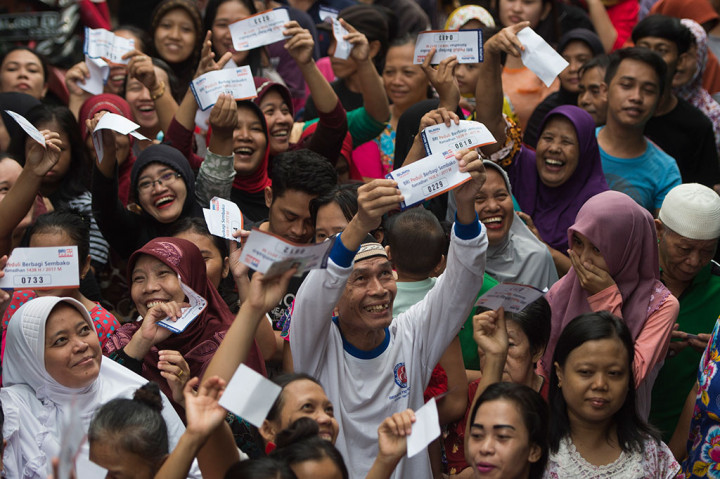 Warga menunjukkan kupon penukaran saat mengantre pembagian sembako.