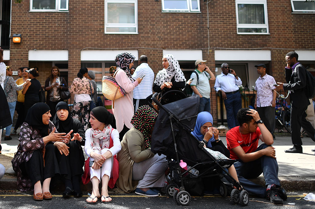 Para korban kebakaran duduk termenung di trotoar.