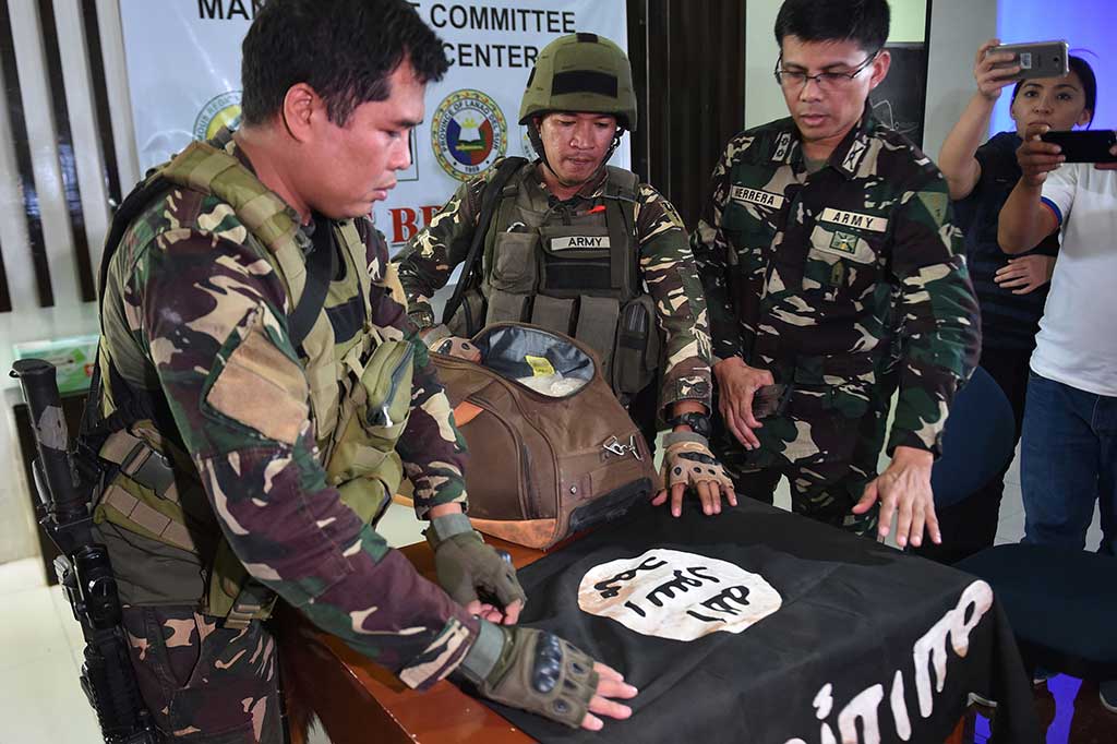 Pasukan militer Filipina menujukkan bendera IS yang ditemukan di sebuah rumah yang diduga sebagai tempat persembunyian kelompok militan Maute, dalam konferensi pers di Marawi, Mindanao, Senin (19/6/2017).