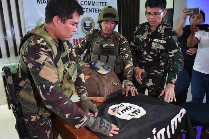 Pasukan militer Filipina menujukkan bendera IS yang ditemukan di sebuah rumah yang diduga sebagai tempat persembunyian kelompok militan Maute, dalam konferensi pers di Marawi, Mindanao, Senin (19/6/2017).