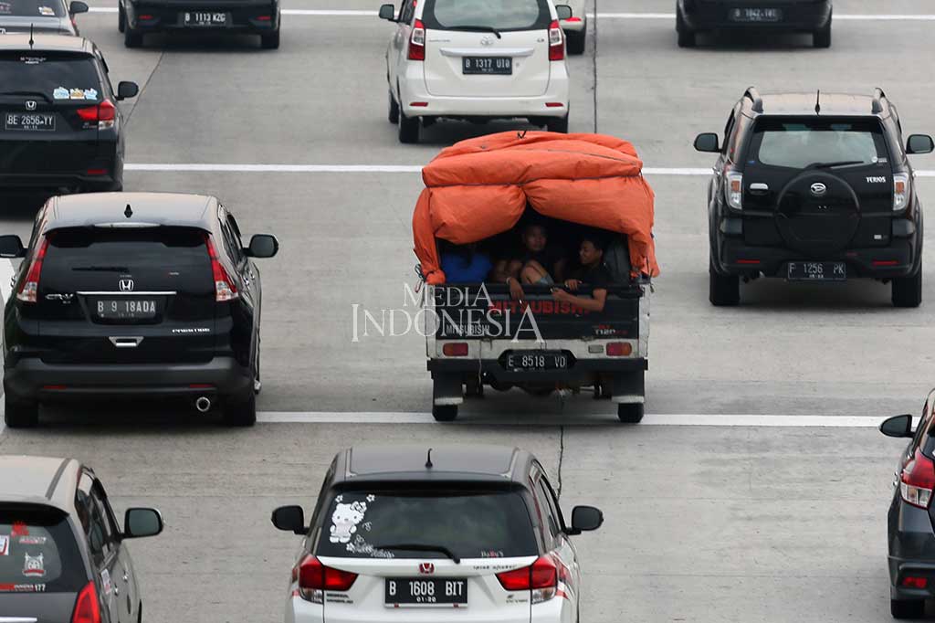 Duduk beratapkan terpal berangka bambu sembari berbagi tempat dengan tumpukan barang bawaan, para pemudik menumpang mobil bak terbuka untuk menuju kampung halaman mereka.