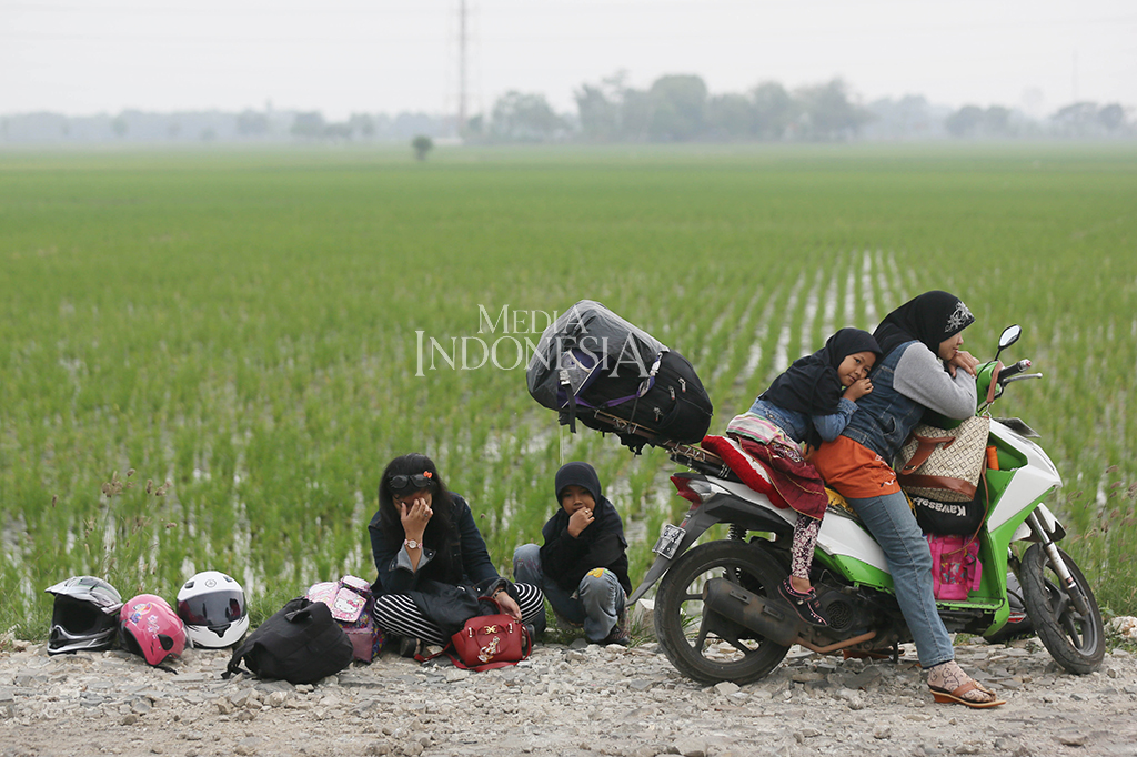 Nampak pemudik sepeda motor sedang beristirahat sejenak di tepi sawah kawasan Cirebon, Jawa Barat.