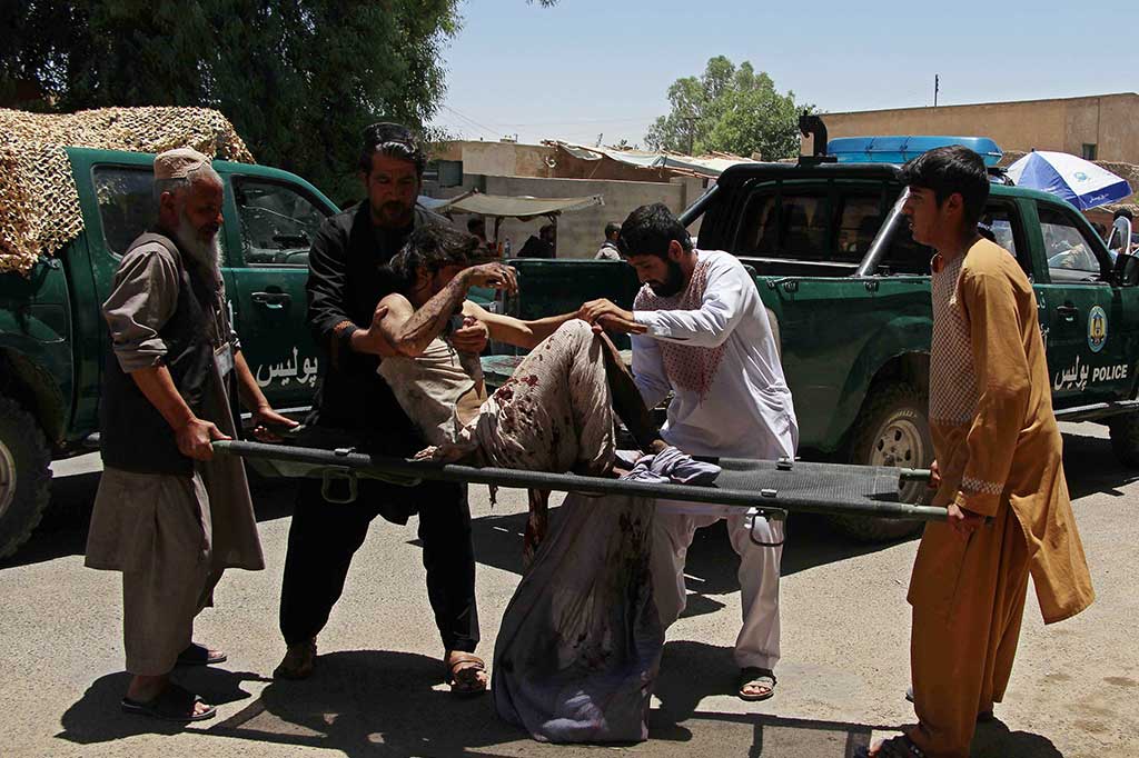 Warga mengevakuasi korban ledakan bom yang terjadi saat warga mengantre di bank untuk mengambil gaji untuk keperluan Idul Fitri. 