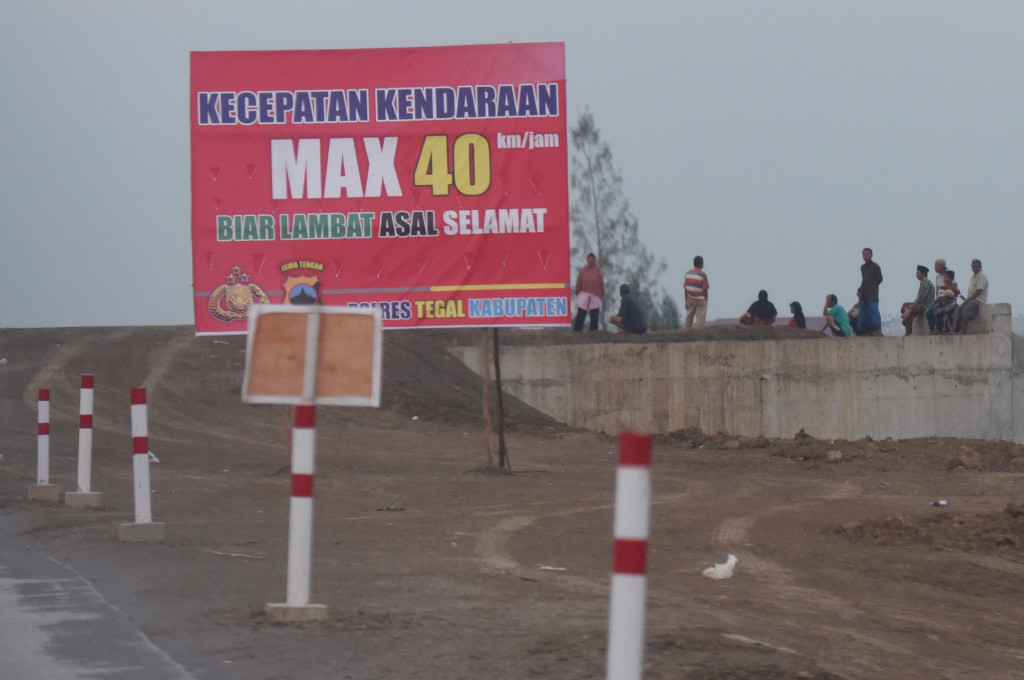 Rambu peringatan batas kecepan maksimal laju mobil. Kondisi jalan masih darurat, minim penerangan dan berdebu tergolong rawan kecelakaan bagi pengemudi yang kelelahan. 
