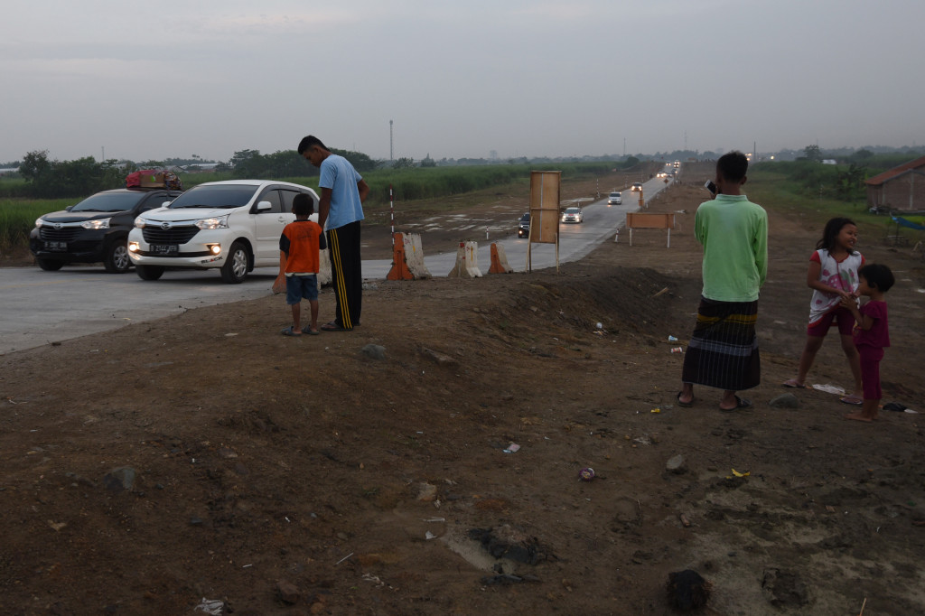 Warga sekitar jalur tol fungsional menonton keramaian ribuan kendaraan yang tiba-tiba melintasi desa tempat tinggalnya.