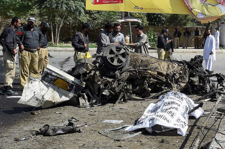 Tubuh korban tewas ditutupi kain di dekat sebuah mobil yang hancur akibat ledakan bom di dekat kantor polisi di Kota Quetta, Pakistan, Jumat (23/6/2017).