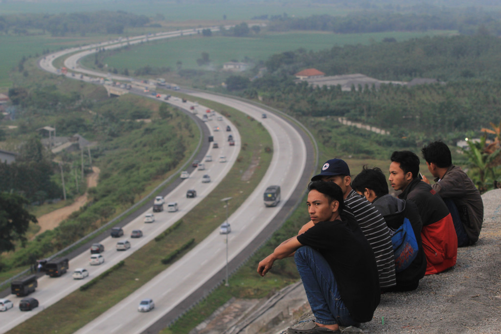 Warga ngabuburit dengan menonton arus mudik dari atas bukit Salam di tepi Tol Cipali, Ciwaringin, Cirebon, Jawa Barat, Jumat (23/6). ANTARA FOTO/Dedhez Anggara