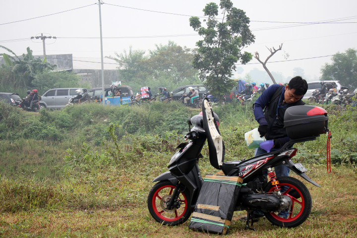 Seorang pemudik sepeda motor mengisikan BBM kemasan sembari beristirahat di Karawang, Jawa Barat, Jumat (23/6/2017). Pertamina menyediakan BBM kemasan untuk mencegah antrian panjang di SPBU yang bisa menyebabkan kemacetan arus mudik. ANTARA FOTO/Galih Pradipta