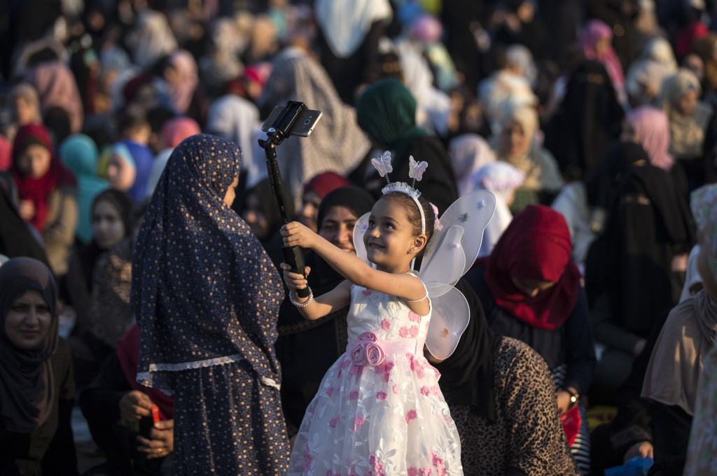 Seorang gadis cilik berkostum bidadari selfie seusai Salat Ied. Kegembiraan di hari raya dirayakan oleh semuanya. 