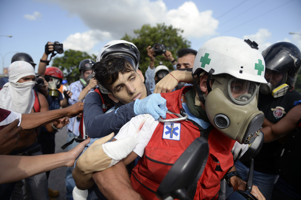 Tim medis membawa pengunjukrasa yang terkena gas air mata. Aksi unjuk rasa yang berlangsung sejak bulan lalu ini sudah memakan korban jiwa. AFP Photo/Federico Parra