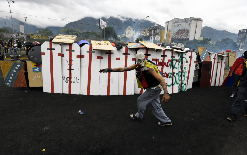 Barikade massa pengunjukrasa menahan tembakan gas air mata polisi. Krisis ekonomi panjang menyebabkan tingkat kemiskinan dan kriminalitas di Venezuela meningkat. AFP Photo/Federico Parra
