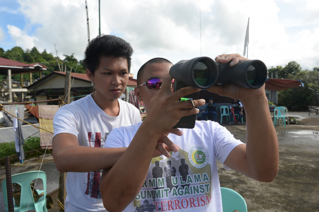 Warga menggunakan smartphone untuk memotret citra aksi bombardir yang muncul di binokular. Pada saat bersamaan di darat berlangsung kontak tembak antara militer Filipina melawan kelompok teroris Maute