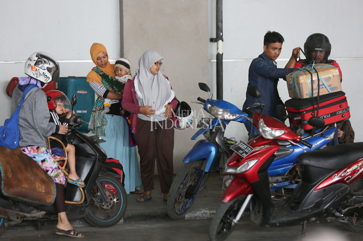 Seorang pemudik sedang merapihkan barang bawaan nya ke atas motor untuk melanjutkan perjalanannya menuju rumah.