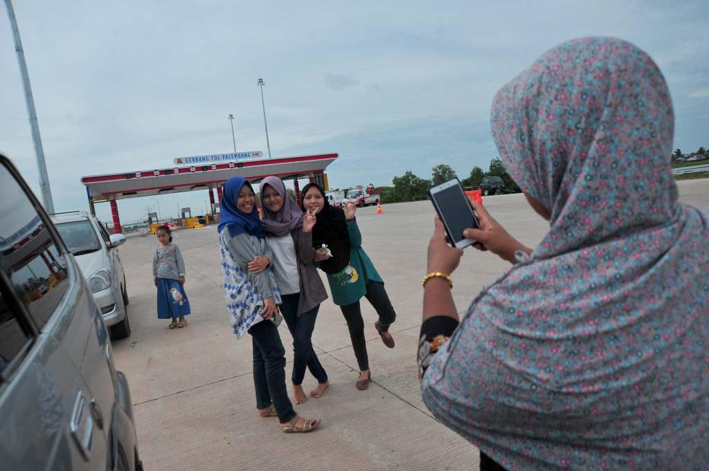 Pengguna tol berfoto sebelum melintasi area tol Palindra, Sumatera Selatan. Jalur tol fungsional musim mudik lebaran dilalui rata-rata seribu kendaraan per hari. ANTARA FOTO/Feny Selly
