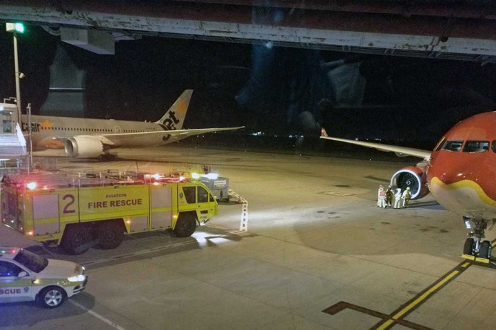 Petugas pemadam kebakaran berada di samping mesin pesawat AirAsia Airbus A330, setelah pesawat tersebut melakukan pendaratan darurat di Bandara Internasional Brisbane, Selasa (4/7/2017). 