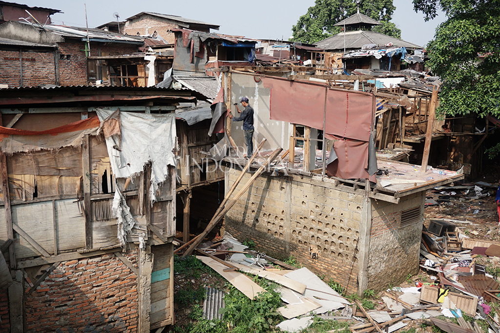Nampak seorang warga sedang membongkar sendiri bangunan rumahnya sekiranya masih ada kayu atau barang barang yang masih bisa di jual.