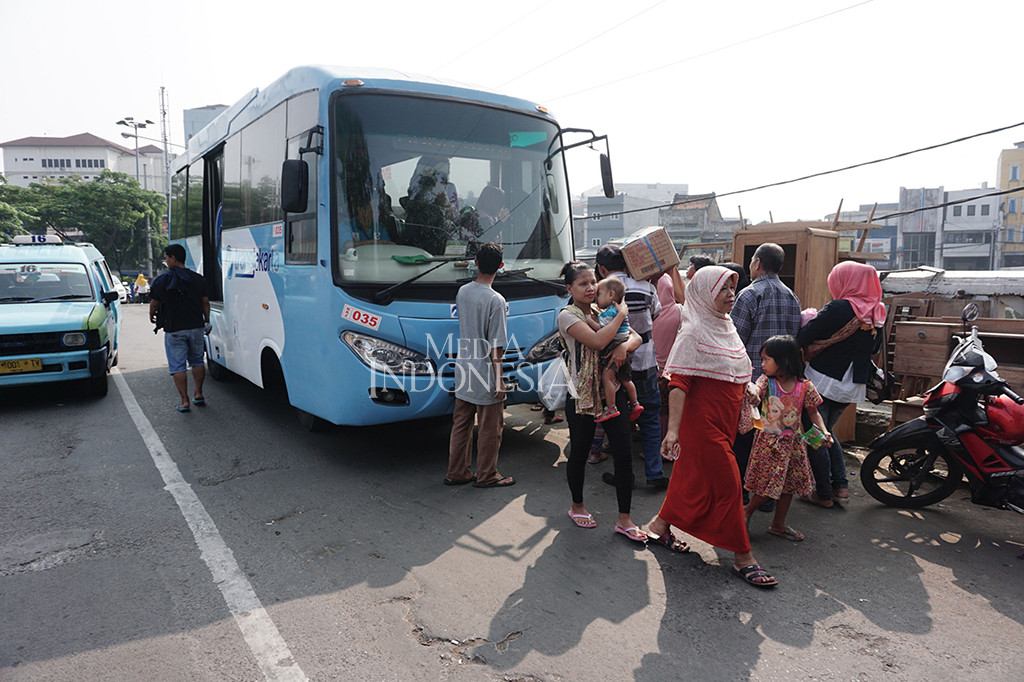 Warga Bukit Duri memindahkan barang-barangnya menggunakan bus Transjakarta.
