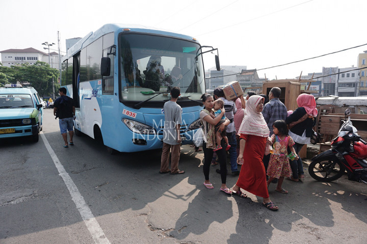 Warga Bukit Duri memindahkan barang-barangnya menggunakan bus Transjakarta.
