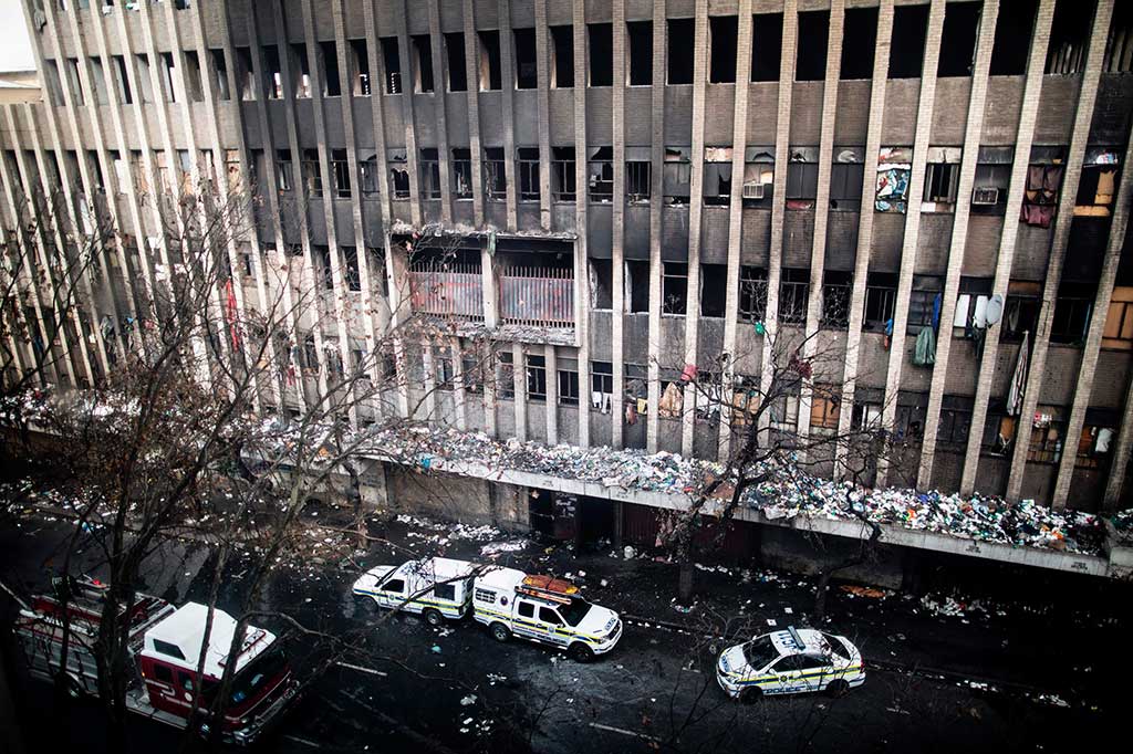 Mobil polisi dan kendaraan darurat berada di luar sebuah blok apartemen yang bobrok dan mengalami kebakaran di pusat bisnis pusat Kota Johannesburg, Rabu (5/7/2017) waktu setempat.