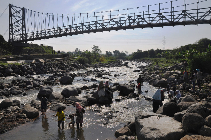 Sejumlah warga bermain sambil menikmati keindahan sungai di bawah jembatan gantung Sekrikil, Parakan,Temanggung Jawa Tengah. Pada libur lebaran pekan lalu, jembatan gantung tersebut diresmikan Presiden Joko Widodo dan kini menjadi lokasi wisata alternatif di Temanggung. ANTARA FOTO/Anis Efizudin