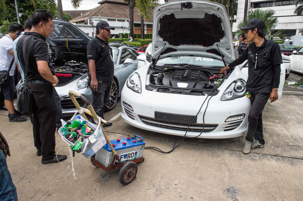 Petugas mencoba menggunakan aki jumper untuk menyalan mesin sebuah sportcar. Akibat lama tidak dirawat dengan baik, banyak mobil mewah ini yang sulit dihidupkan mesinnya.