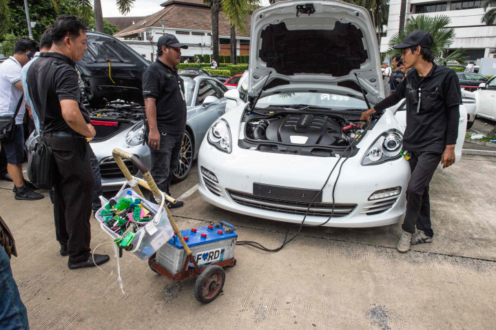 Petugas mencoba menggunakan aki jumper untuk menyalan mesin sebuah sportcar. Akibat lama tidak dirawat dengan baik, banyak mobil mewah ini yang sulit dihidupkan mesinnya.