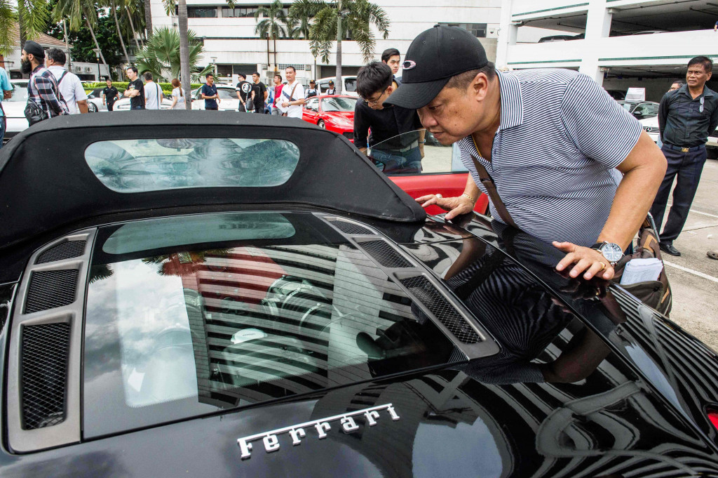 Seorang calon pembeli memeriksa interior sebuah Ferrari yang dilelang. Sebagian besar dalam kondisi sangat baik tapi kurang terawat. 