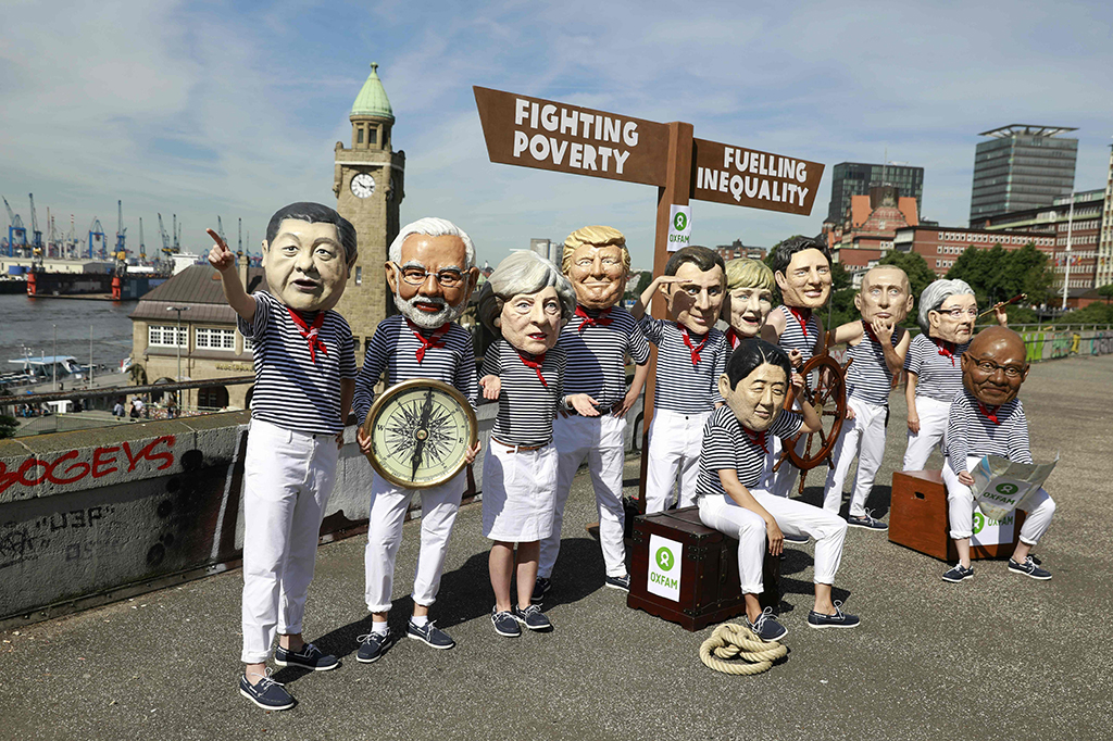 Sementara itu aktivis anti kapitalis melakukan aksi dengan mengenakan topeng para pimpinan negara G20 di Hamburg, Jerman Utara, Kamis (6/7/2017). Salah satu poin yang diserukan mereka adalah kesetaraan dan menutup jurang antara kaya dan miskin. 