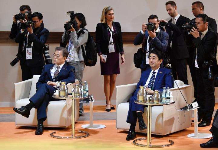 Presiden Korea Selatan Moon Jae-in dan PM Jepang Shinzo Abe berdampingan di pertemuan retreat KTT G20. Dua negara industri ini merupakan dua raksasa Asia yang sangat berpengaruh dan bersaing satu sama lain. AFP PHOTO AND POOL / John MACDOUGALL