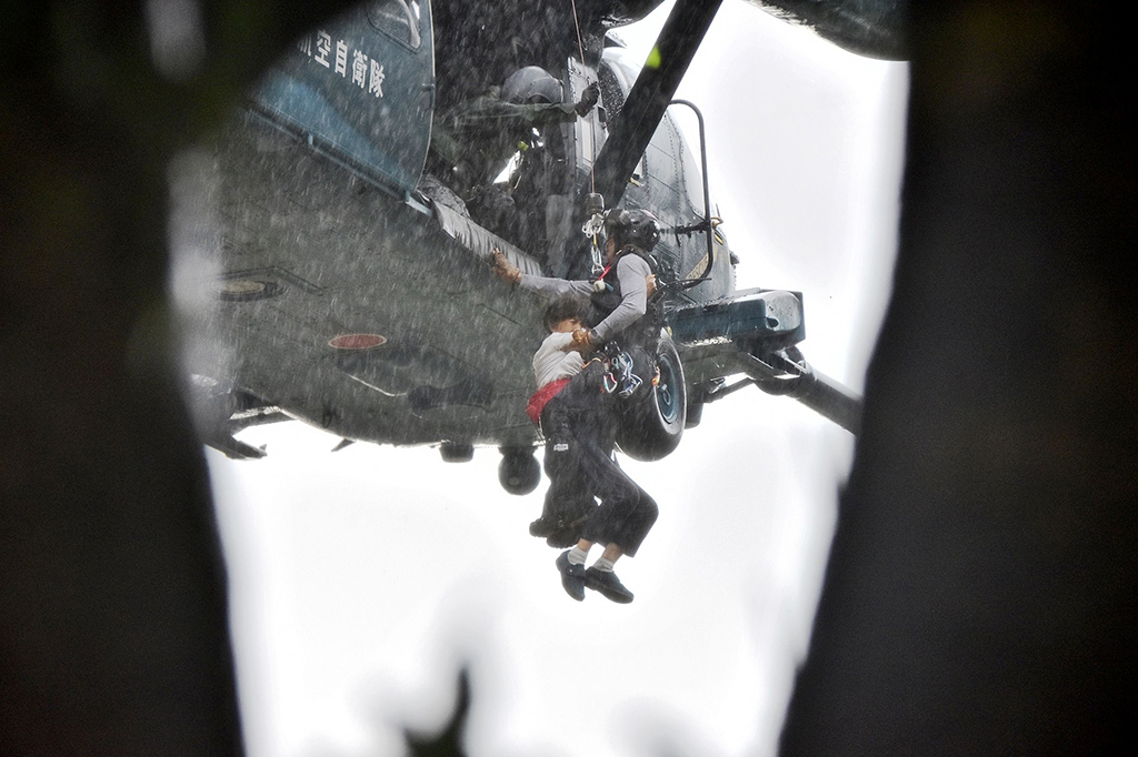 Tim SAR harus menembus hujan lebat saat mengevakuasi para korban yang terjebak banjir bandang di Asakura, Fukuoka.
