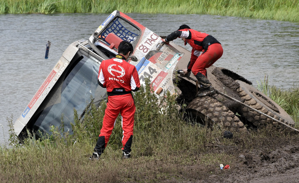 Teruhito Sugawara dan Hiroyuki Sugura memanjat keluar dari truk Hino pacuannya yang terperosok lumpur bantaran sungai kecil di Tcheboksary, Minggu (9/7/2017). 
