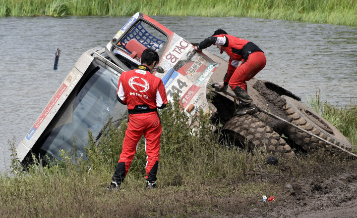 Teruhito Sugawara dan Hiroyuki Sugura memanjat keluar dari truk Hino pacuannya yang terperosok lumpur bantaran sungai kecil di Tcheboksary, Minggu (9/7/2017). 
