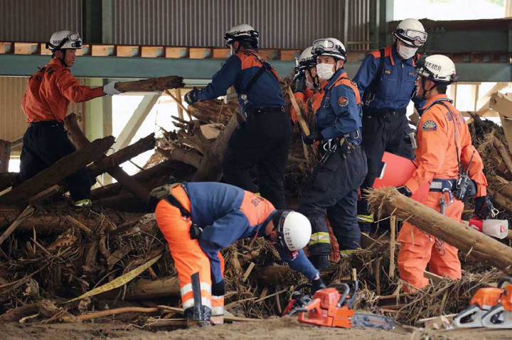 Petugas pemadam kebakaran berupaya menyingkirkan puing-puing kayu berserakan yang tersapu banjir bandang di Asakura.