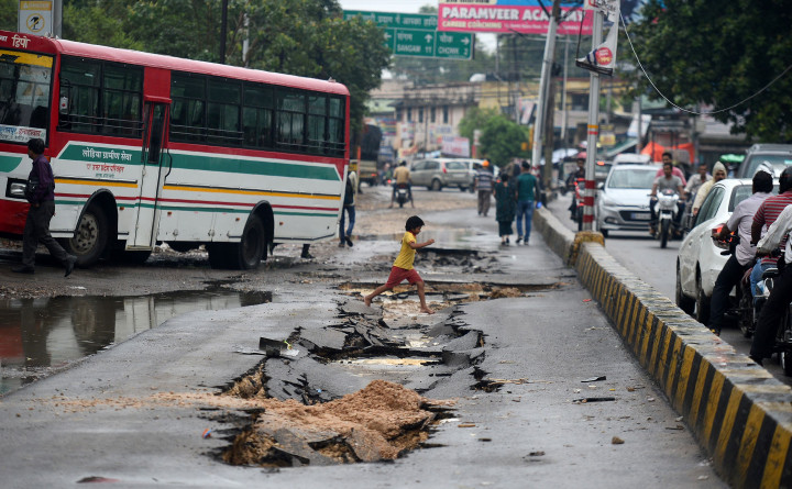 Seorang anak melompati ruas jalan yang rusak akibat banjir di Allahabad, India. Hujan sangat deras akan sering tercurah di India selama musim penghujan.