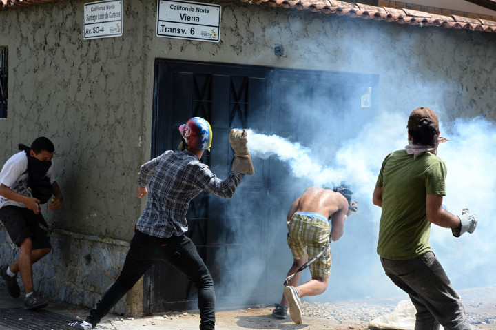 Pengunjukrasa melempar balik kaleng gas air mata ke arah polisi anti huru hara. Tuntutan massa berkembang menjadi pengunduran diri Moduro sebagai Presiden Venezuela dan kini pembebasan tokoh oposisi Leopoldo Lopez dari penjara. AFP PHOTO / Federico Parra 