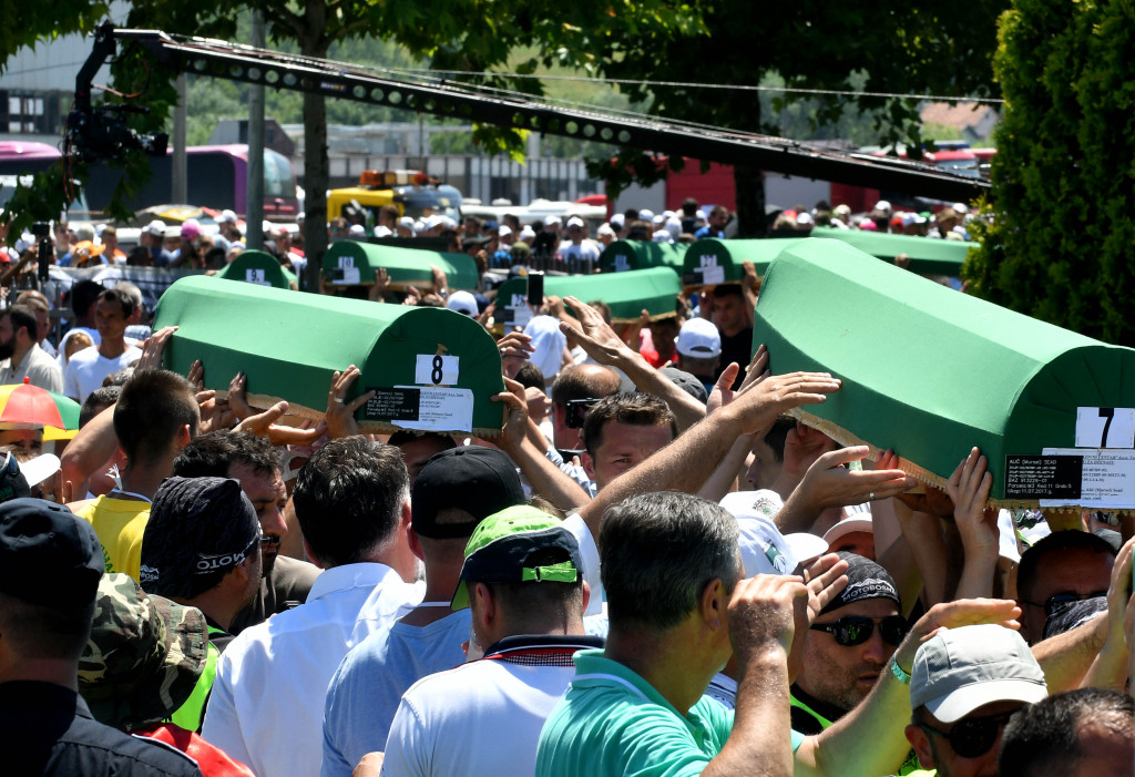 Keranda berisi jenazah korban diusung secara berantai dari truk ke pemakaman. Keluarga korban berdatangan dari berbagai negara di Eropa tempat mereka mengungsi.