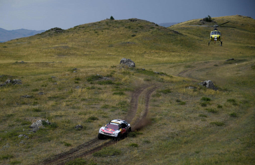 Helikopter panitia terbang di atas Peugeot 3008 Maxi yang dikendarai Stephane Peterhansel dan rekan senegaranya Jean Paul Cottret dari Perancis. 