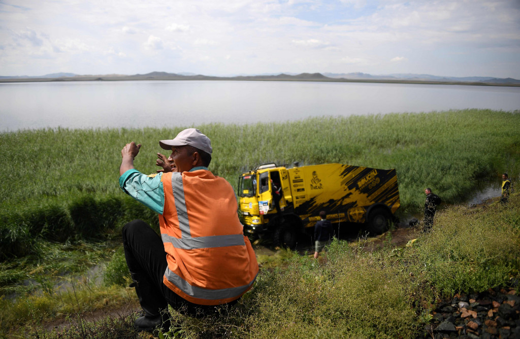 Seorang marshall mempenyaksikan Michel Boucou dan Jean-Jacques Martinez sedang dievakuasi dari kubangan lumpur yang menghentikan laju truk balap itu. 