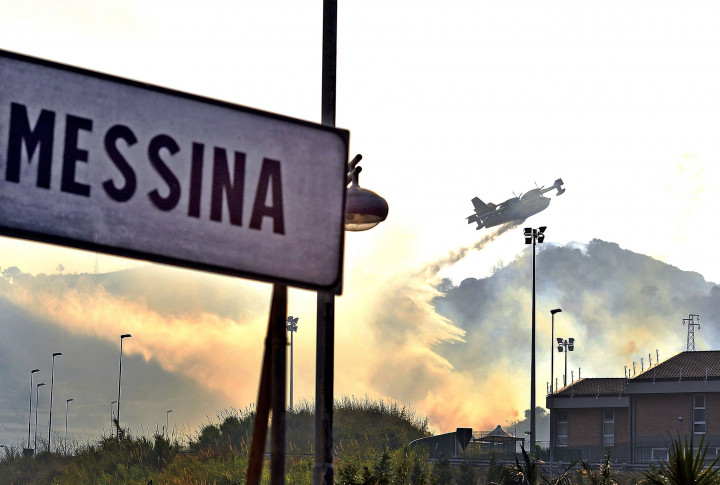 Pesawat pemadam kebakaran melepaskan bom air di atas wilayah hutan yang sedang terbakar. 