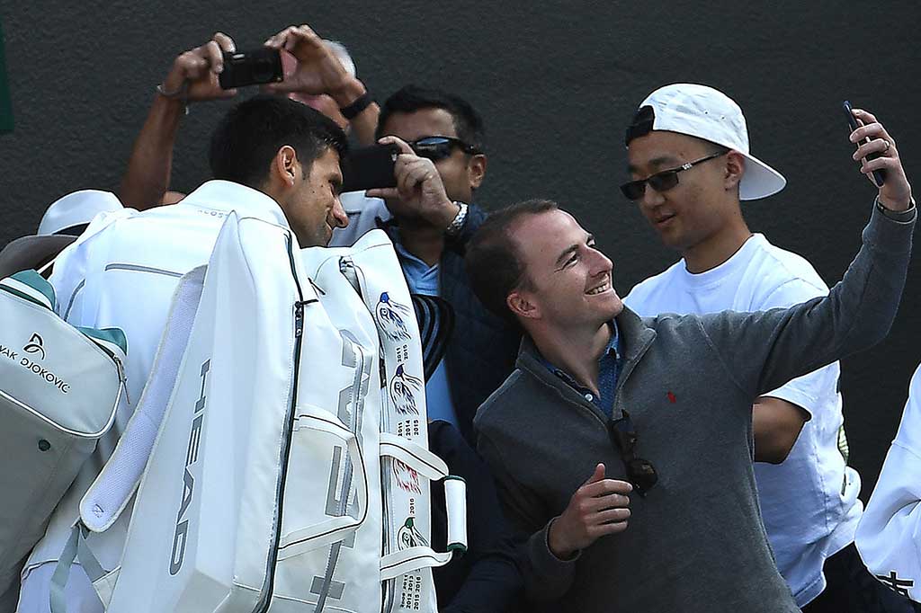 Djokovic melayani permintaan foto dari penggemarnya saat akan meninggalkan lapangan.  AFP/Glyn Kirk